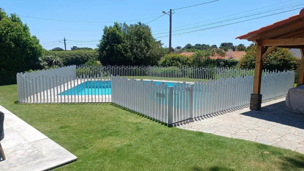 Imagem mostra um cercado de piscina feito em metal que harmoniza bem com a area externa da casa.